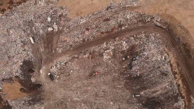 City dump or big garbage dump with trucks and bulldozers, aerial view, flight on drone above