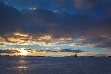 Winter snowy field and a blue sky with clouds