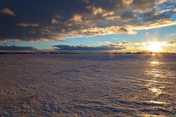 Winter snowy field and a blue sky with clouds