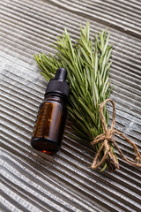 Rosemary essential oil on a gray wooden rustic background