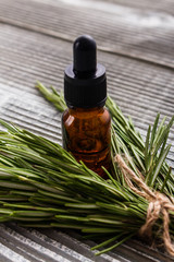 Rosemary essential oil on a gray wooden rustic background