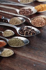 Different spices in  spoons on a wooden background.