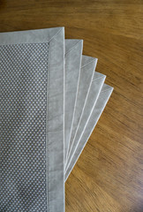 Many golden colored place mats open as fan over wooden table background