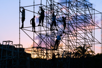 Los obreros están trabajando en el andamio al atardecer.