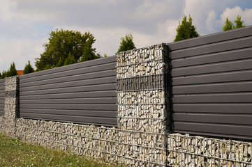 Wall. House fence with an interesting use of gabions and steel panels.