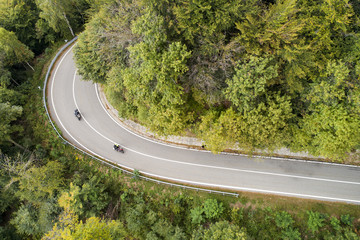 Mountain road in the woods with motorcycle. Aerial view.