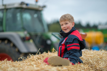 Boy smiling on hay stack at farm