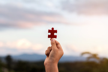 Fototapeta hands holding piece of red jigsaw puzzle obraz