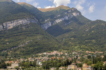 Fototapeta na wymiar View from Lake Como to a small town at the foot of the Alpine hills, Italy.