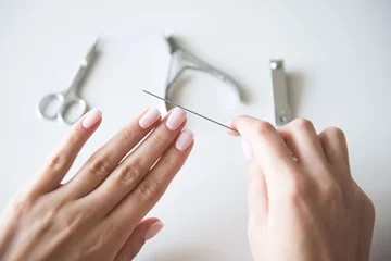 Poster Woman making manicure with nail care tools background. French manicure. © alexngm
