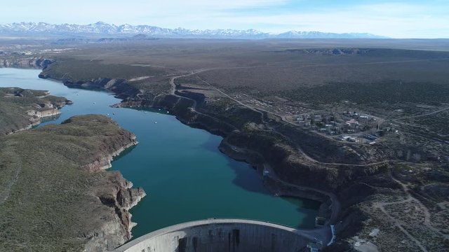 Aerial drone scene of Agua de Toro dam at San Rafael, Mendoza, Cuyo Argentina. Camera moving backwards discovering semi cirucular concrete dam structure. View of lake and high mountains at background