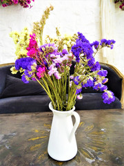 Composition of beautiful dried colored flowers in a white vase on an old table 