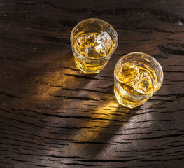 Whiskey glasses or glasses of whiskey with ice cubes on the wooden table. Top view.