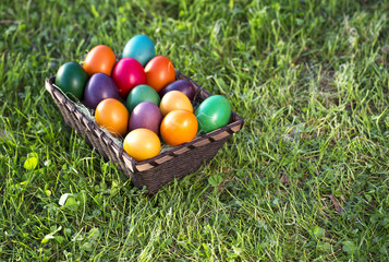 Top view of handmade Easter eggs colored in different patterns on green grass.  Copy space.