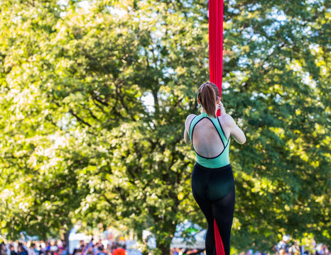 Young Aerial acrobatic dancer is climbing a red silk ribbon