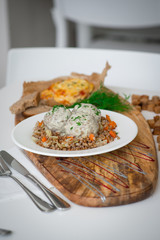 Meatballs with sauce and buckwheat. The dish stands on a beautiful board. Тефтели с соусом и гречкой. Блюдо стоит на красивой доске.