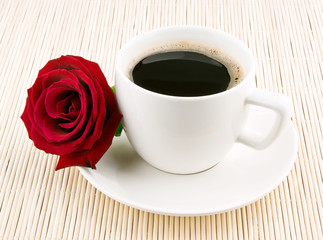 Coffee cup and rose on table