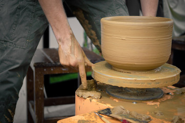 Young man creating a clay jar on a potter's wheel