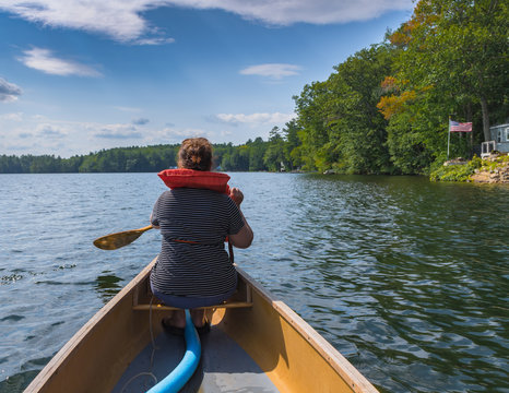A woman is paddling in a canoe in a lake