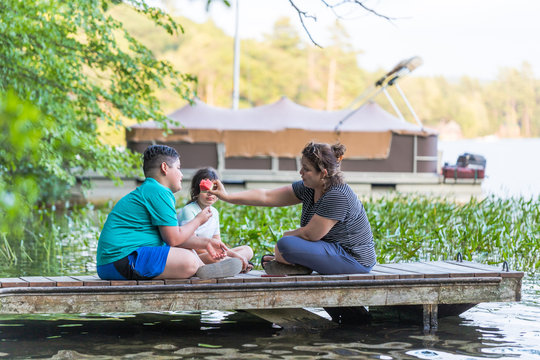 A woman is sharing a piece of watermelon with her son while sitting on a dock