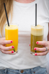Apple and orange fresh juices in the hands of a girl on a white background. Яблочный и апельсиновый свежевыжатые соки в руках у девушки на белом фоне.