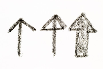 Black color oil pastel drawing in arrow shape on white paper background