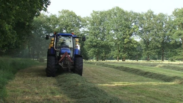 Tractor collects hay from field with a bale slicer.  