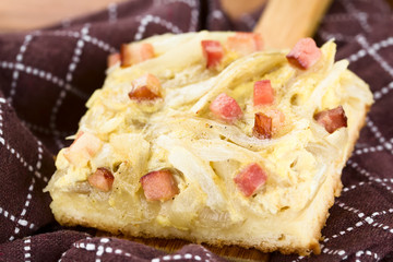 Frischer hausgemachter gebackener Zwiebelkuchen, ein deutscher traditioneller herzhafter Kuchen aus Hefeteig belegt mit Zwiebeln, Speck, Ei und Sahne (Selektiver Fokus)