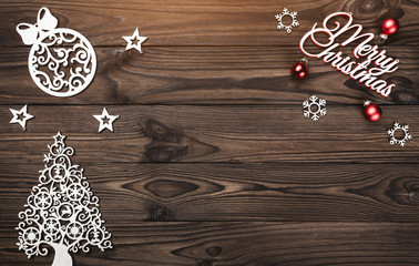 View from above of a Merry Christmas inscription and handmade tree toys on wooden background, greeting card with space for text writing, with light bulbs