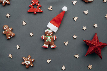 Christmas toys and gingerbread in the form of a traditional ginger man with a Santa Claus hat on a gray background. Christmas or New Year background.