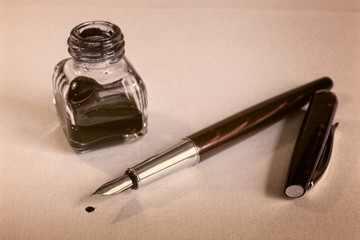 Burgundy fountain pen, blue ink and inkwell on white paper sheet