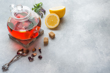Glass teapot with tea, mint and lemon on grey table with copy space