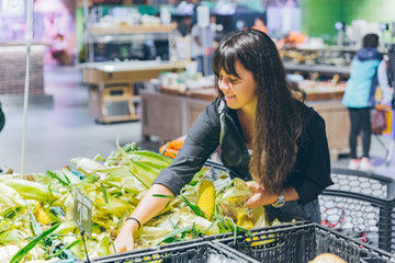 woman choosing corn in grocery shop © phpetrunina14