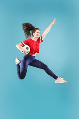 Forward to the victory.The young woman as soccer football player jumping and holding the ball at...