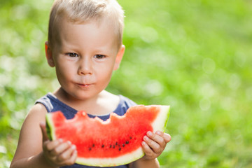 Cute toddler eating a slice of watermelon