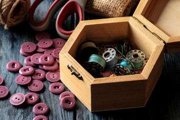 Accessories for sewing and needlework. casket with bobbins close-up on a dark blue wooden background
