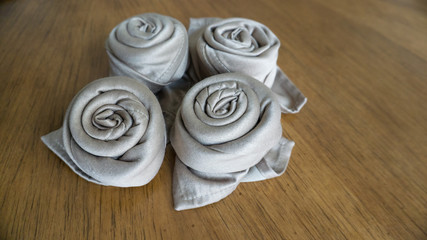 Four golden napkin origami roses over a wooden background ready for events, parties celebrations and holidays