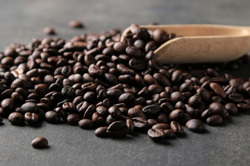 Fried coffee beans close-up and wooden spoon on a black background