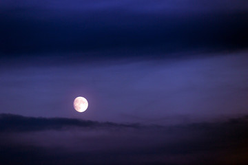 Full moon shining on the sky in cloudy day.