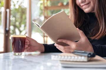 Closeup image of a business woman reading a book while drinking coffee in cafe