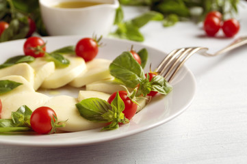 Caprese salad with ripe tomatoes and mozzarella with fresh Basil leaves. Italian food.