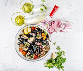 Homemade seafood Black pasta spaghetti with clams mussels octopus vongole in pan with white wine on marbled background
