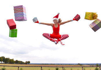 A young girl wearing a Santa Claus  hat shows her happy  feelings for Christmas with jumping up in mid air performing  gymnastic poses. Christmas presents fly all around her from  everywhere.