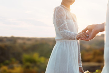 Happy bride and groom holding hands outdoors, closeup