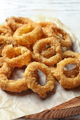 Homemade crunchy fried onion rings on wooden board, closeup