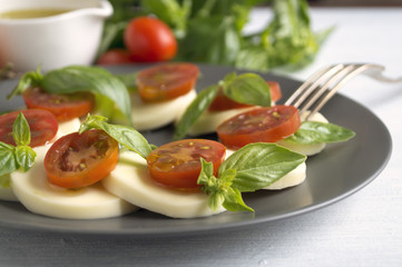 Caprese salad with ripe tomatoes and mozzarella with fresh Basil leaves. Italian food.