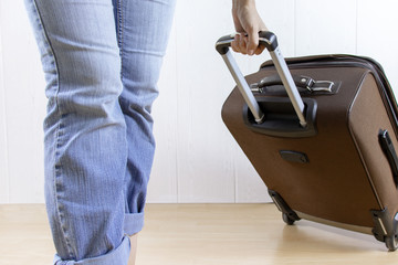 Young woman wearing jeans carry a luggage bag. Travel and relocation concept.