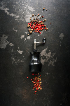 Peppercorns And Pepper Mill On A Dark Rustic Background.Top View, Flat Lay.