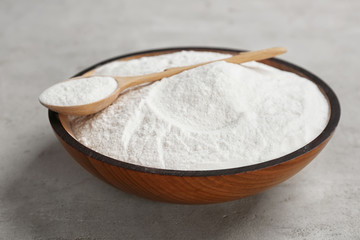 Bowl and spoon with baking soda on gray table