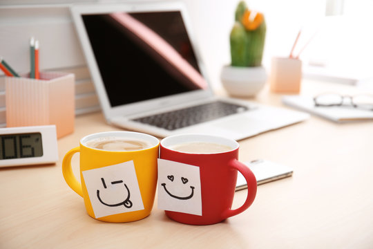 Sticky Notes With Funny Faces Attached To Cups Of Coffee On Office Table. Break Time